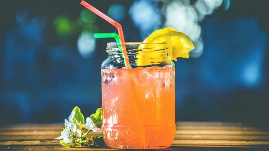 Colorful drink in jar with lemon slice.