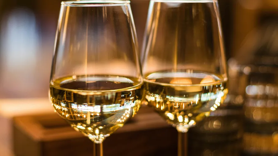 Two filled wine glasses on a table.