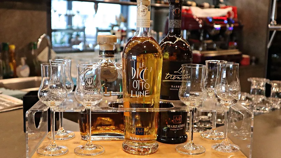 Bottles of grappa with glasses in bar setting.