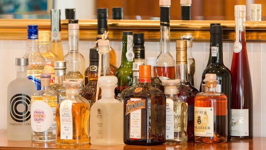 Various liquor bottles on a mirrored shelf.