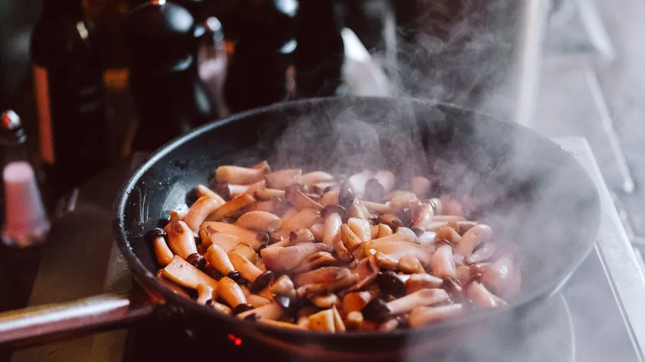 Mushrooms cooking in a steaming pan.