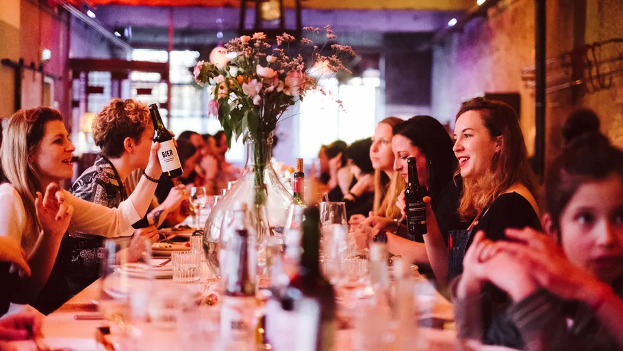 Gruppe speist an langem Tisch, genießt Getränke.