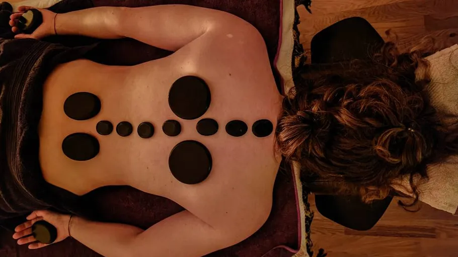 Person receiving hot stone massage on back.