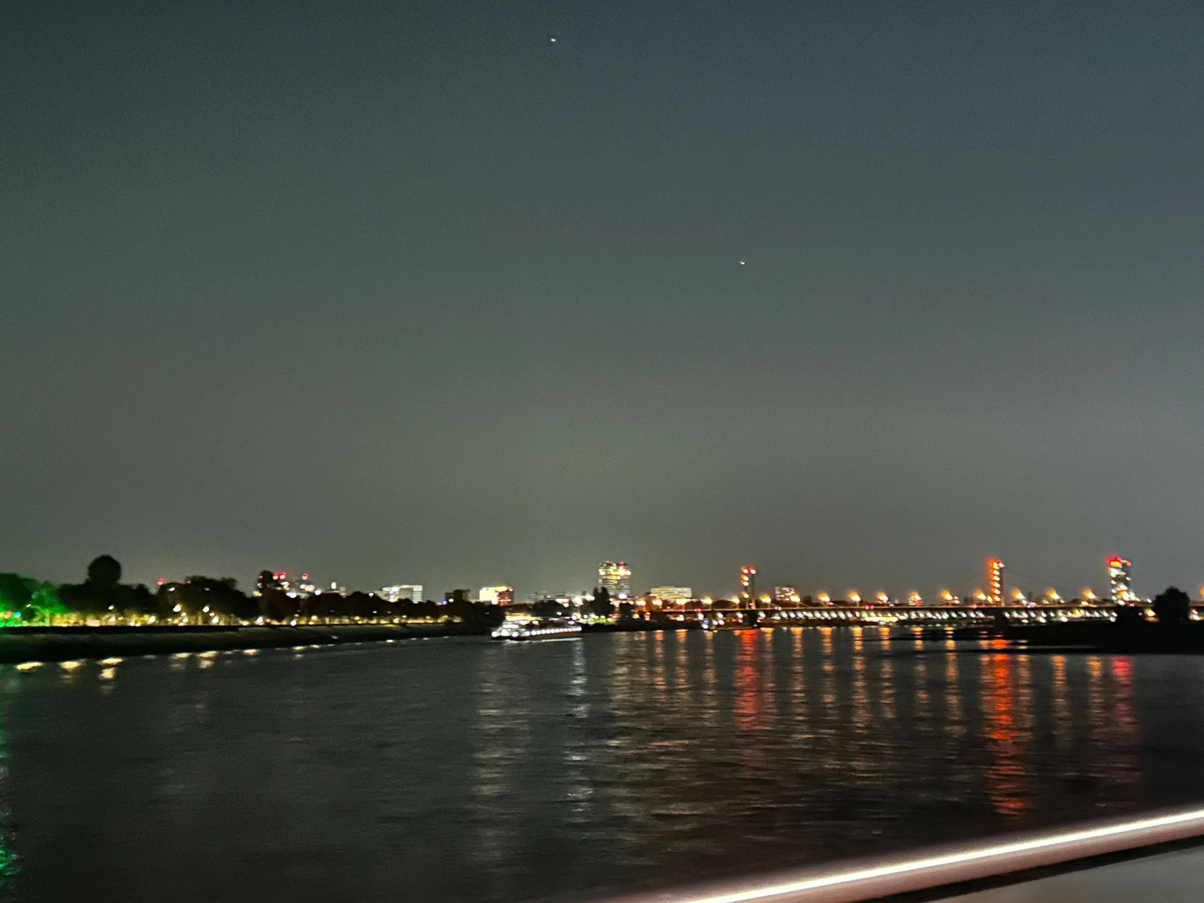Stadtlichter spiegeln sich nachts im ruhigen Fluss.