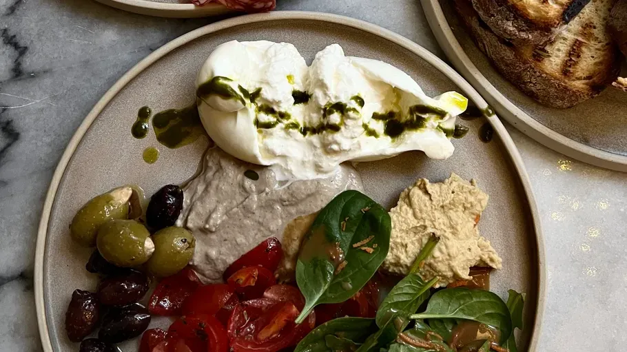 Plate with burrata, olives, and vegetables.
