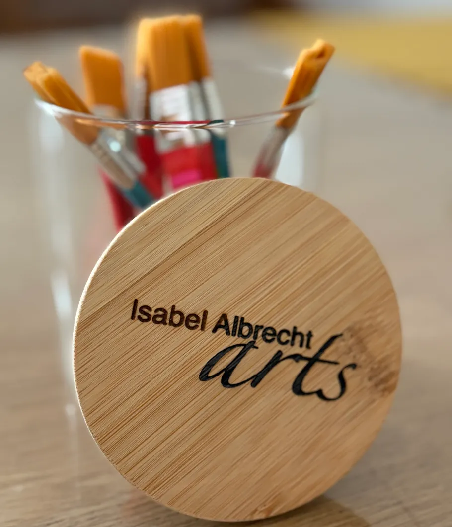 Paintbrushes in jar with wooden lid.