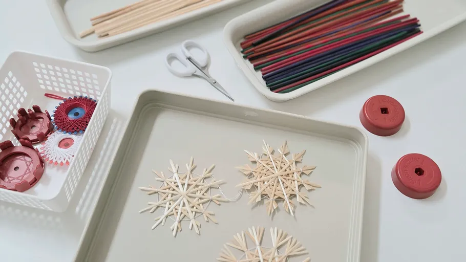 Bastelmaterialien auf Tisch zum Schneeflockenmachen.