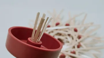 Sticks in red holder, blurred background.