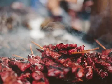 Grilled meat skewers lie in thick plumes of smoke.