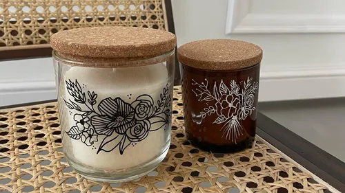 Two decorated candles with cork lids on chair.