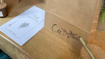 Braune Papiertüte mit Stift auf Tisch.