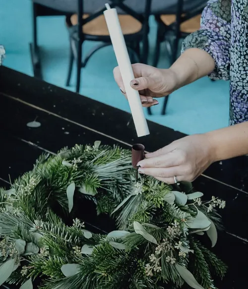 Person placing candle in a wreath.