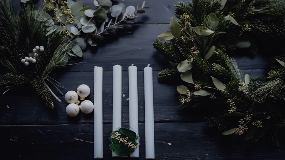 Candles surrounded by greenery and festive decor.