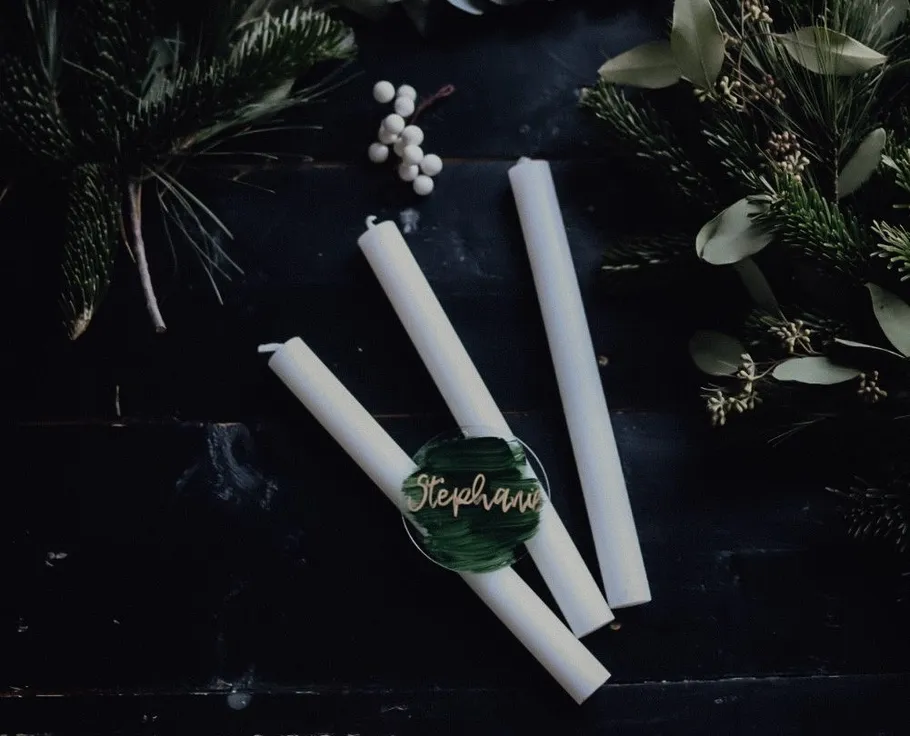 Three candles and greenery on dark background.