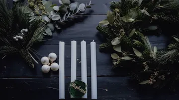 Candles and wreaths on a dark table.