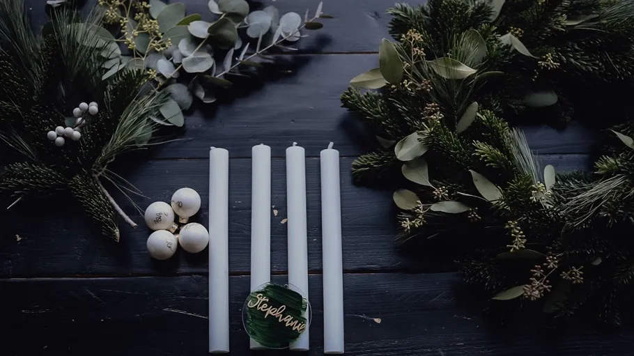 Candles and wreaths on a dark table.