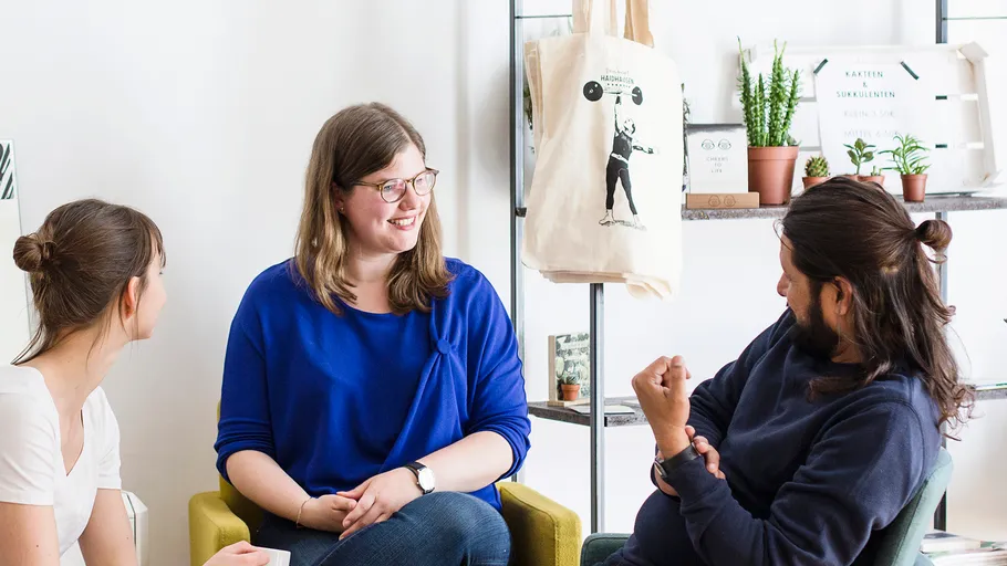 Drei Personen plaudern locker im Wohnzimmer.