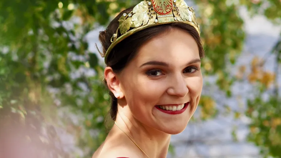 Smiling woman wearing a crown, outdoors.