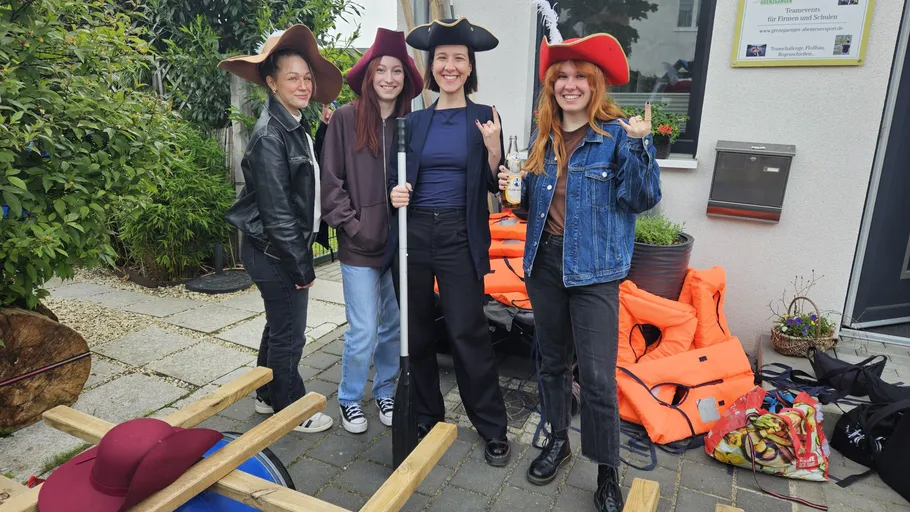Four women wearing pirate hats in a garden.