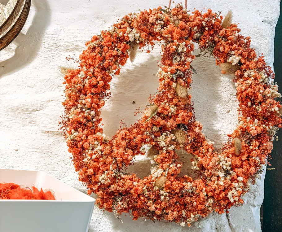 Floral peace sign wreath on white wall.
