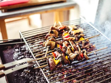 Grillspieße brutzeln auf einem heißen Grill in einem Raum.