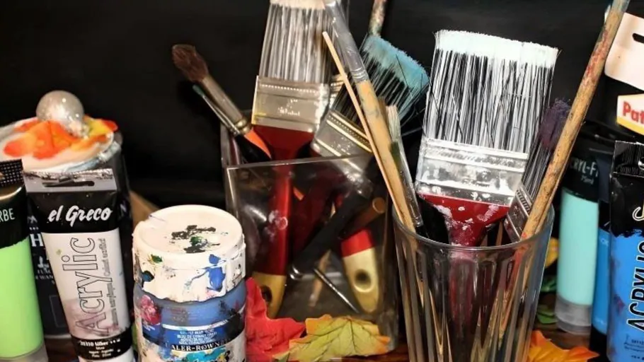Verschiedene Pinsel und Farben auf einem Tisch.