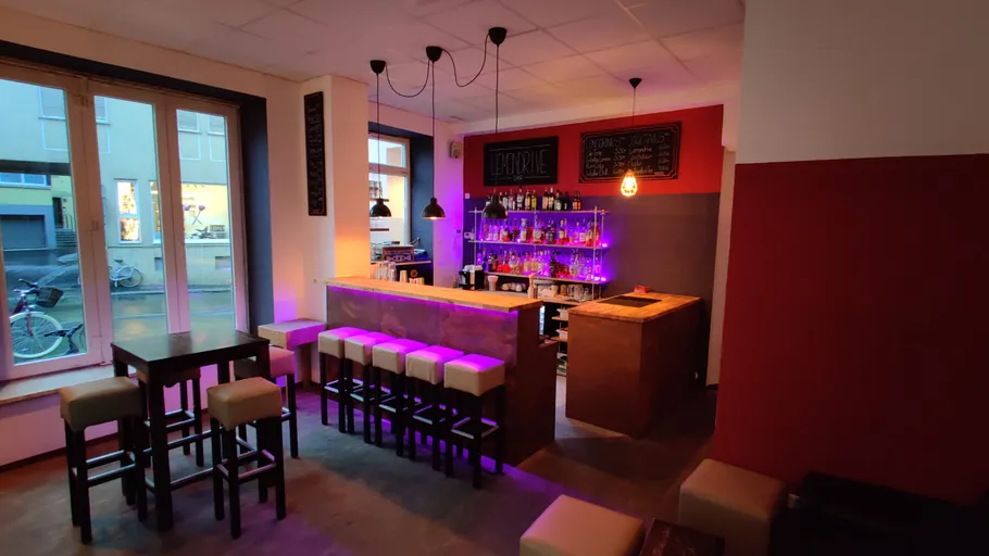 Cozy bar with stools and illuminated shelves.