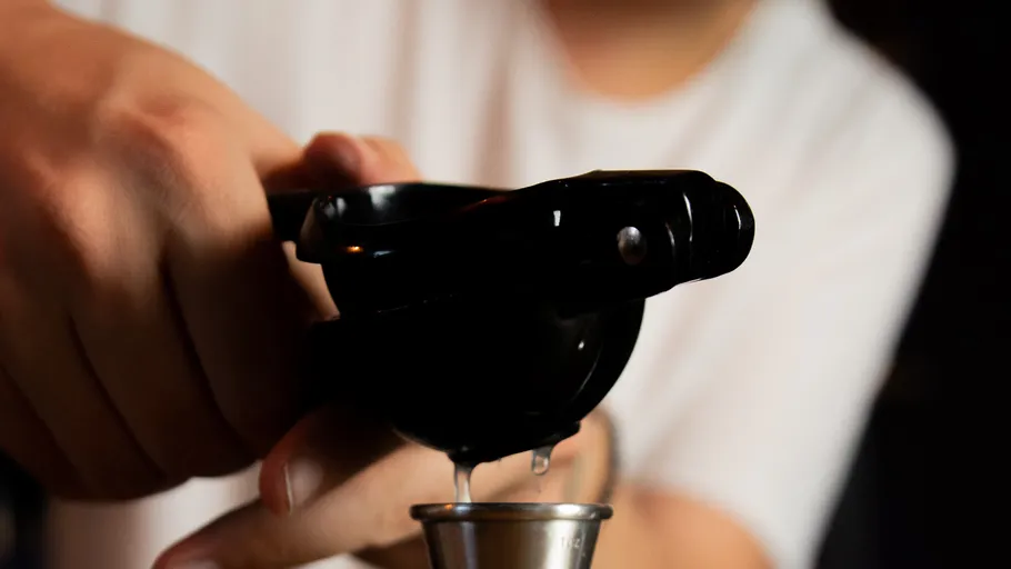 Hand presst Zitronensaft in Messbecher.