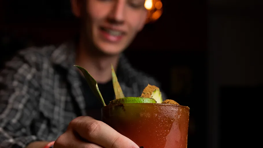 Person serving a drink with fruit garnish.