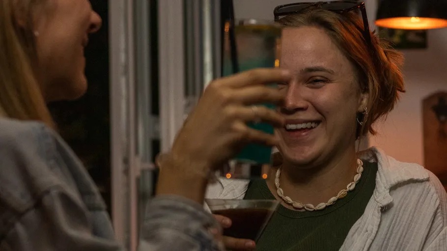 Zwei lachende Personen mit Getränken drinnen.