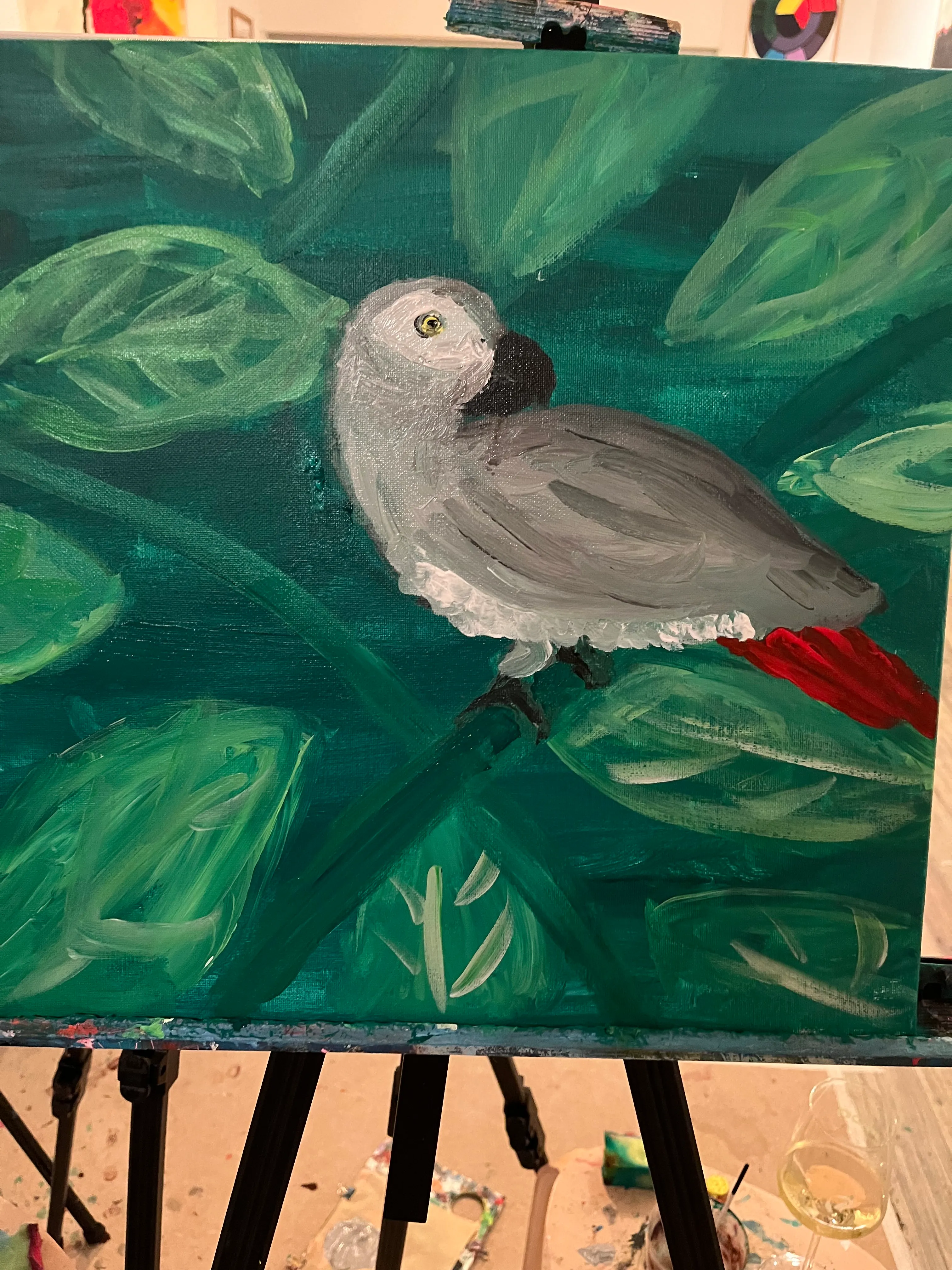 Parrot painted on canvas with leafy background.