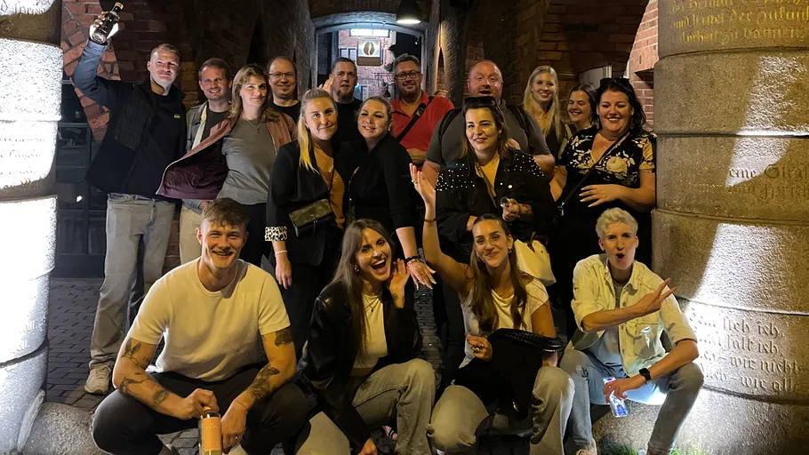 Group of people posing in brick corridor.