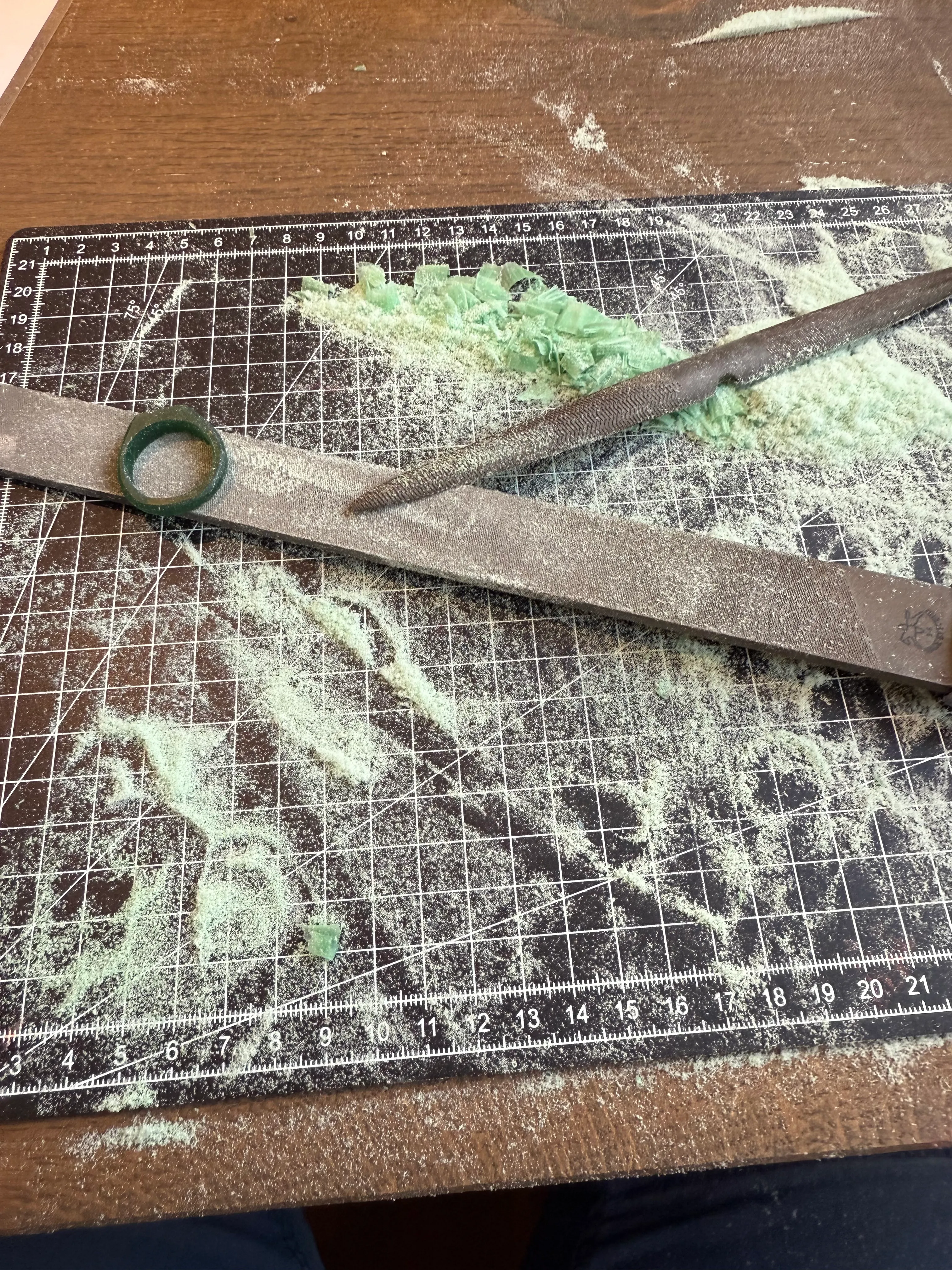 Feilen und grüner Staub auf Schneidematte.