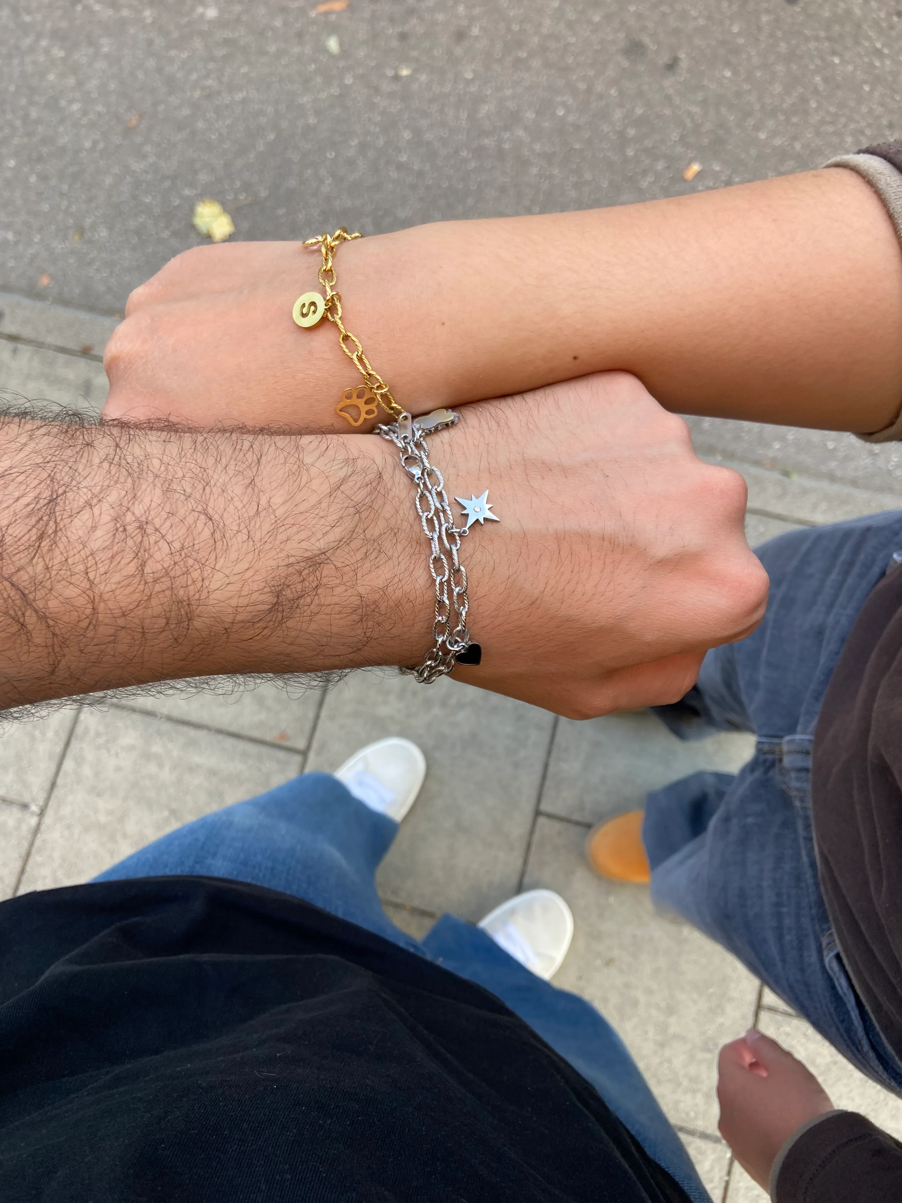 Zwei Handgelenke mit Armbändern auf Gehweg.