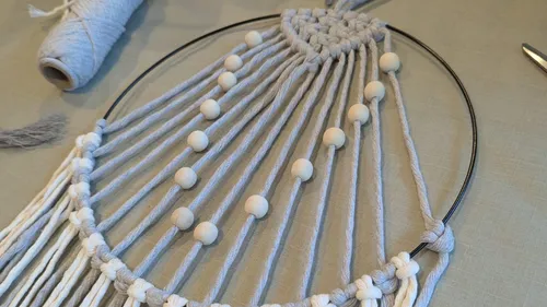 Makramee-Ring mit Perlen auf Tisch.