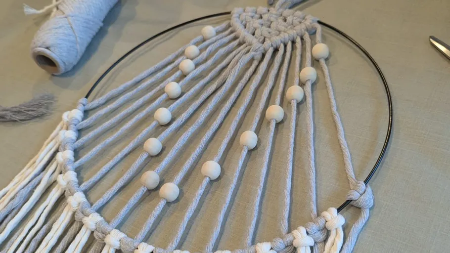 Makramee-Ring mit Perlen auf Tisch.