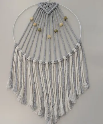 Macrame wall hanging with beads on light background.