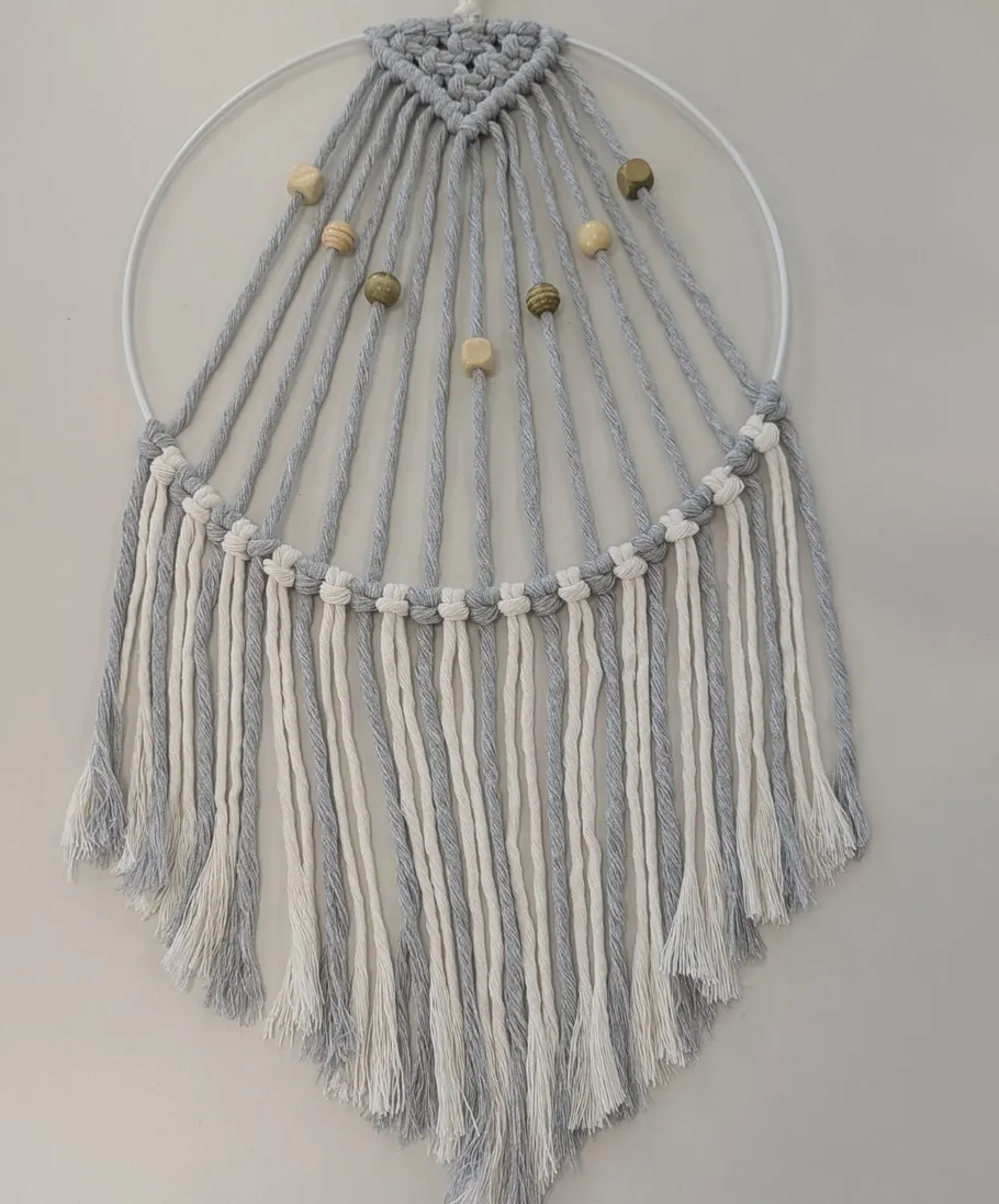 Macrame wall hanging with beads on light background.