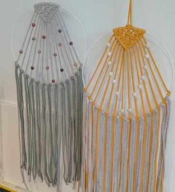 Two macramé hangings with beads on a wall.