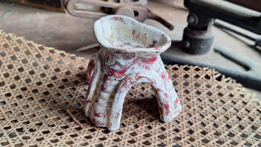 Keramikobjekt mit roter Glasur auf Geflechtmatte.