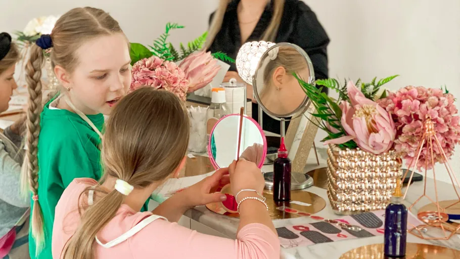 Girls looking at mirror, beauty-themed table decoration.