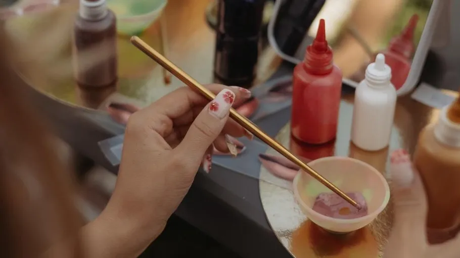 Hand holding brush, mixing color in bowl.