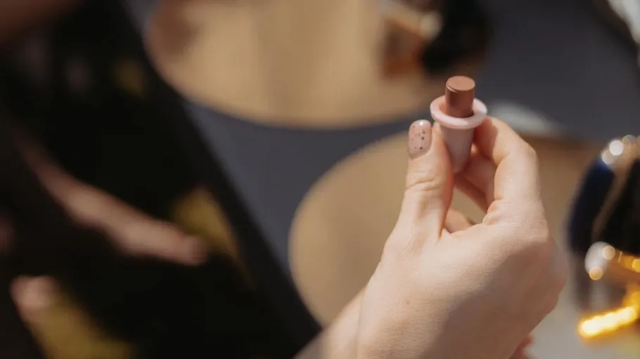 Hand holding lipstick, blurred background.