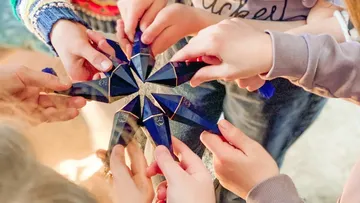 Hands holding star-shaped arrangement of sticks.