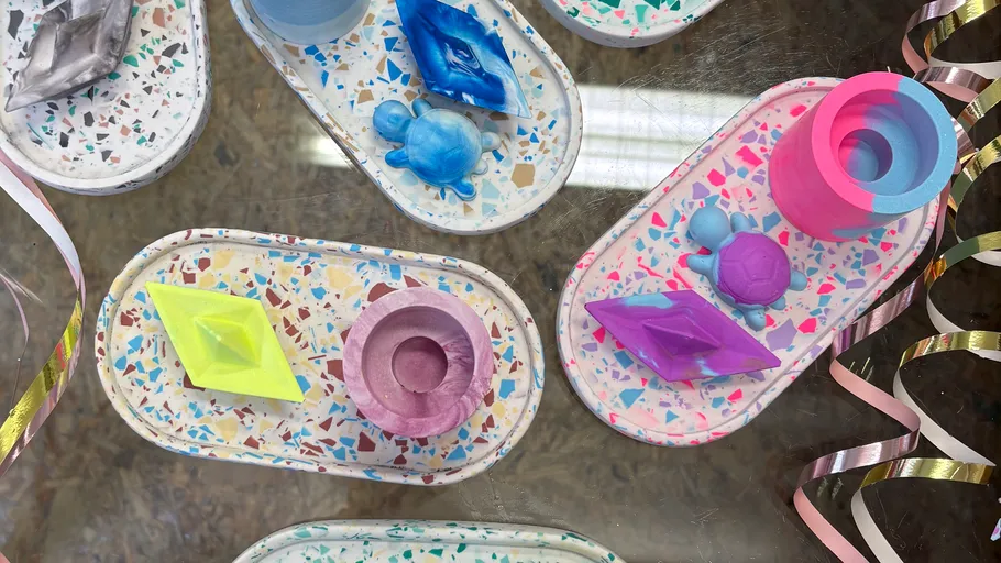 Bunte geometrische Objekte auf Terrazzo-Tabletts platziert.