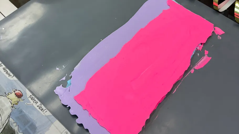Pink and purple clay on dark surface.