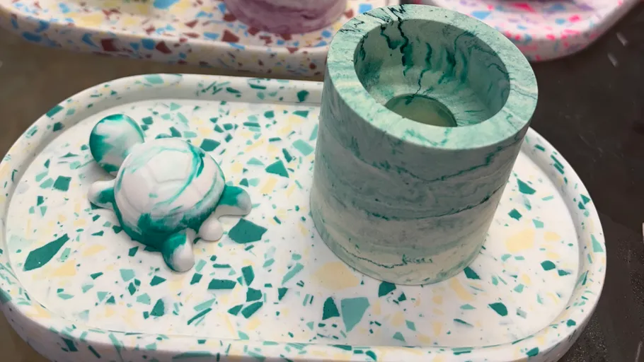 Grüne Marmorschildkröte und Becher auf geflecktem Tablett.