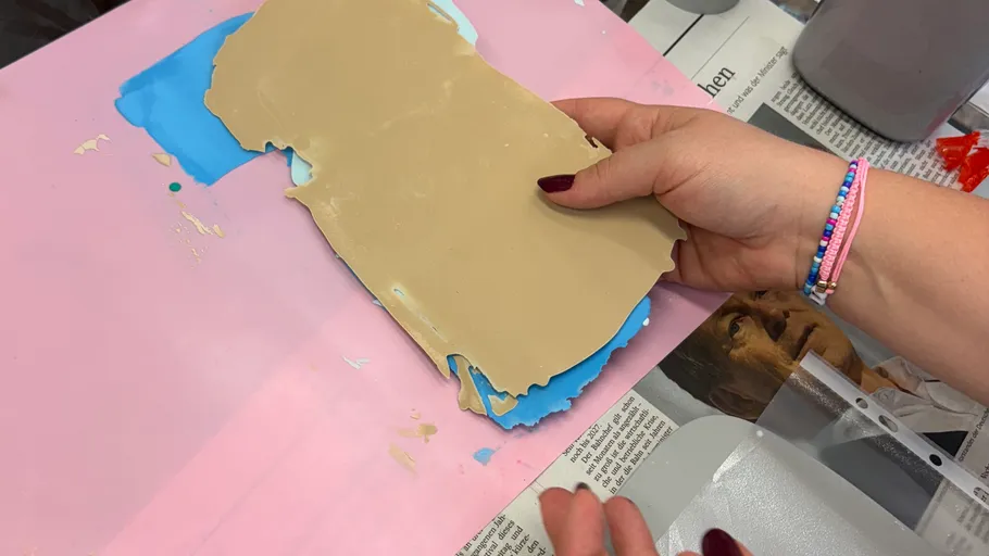 Hands preparing dough on a pink surface.
