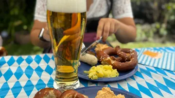 Bier und bayerisches Essen auf blauem Tuch.