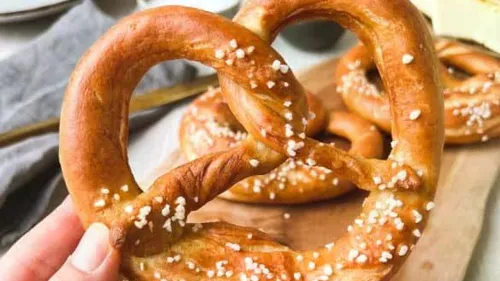 Hand hält gesalzene Brezel in Küche.